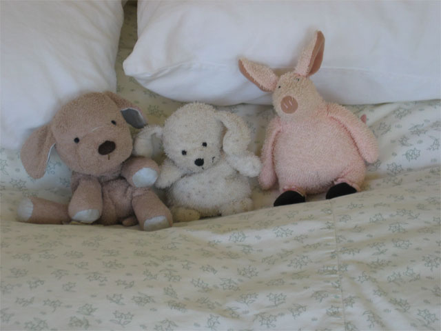 Three stuffed animals on a bed.