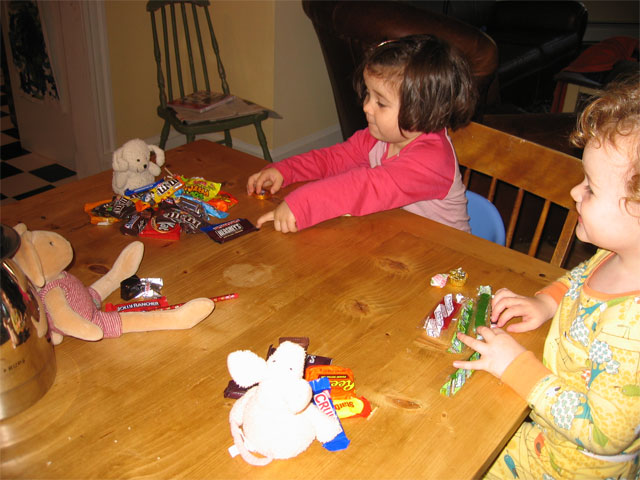 two toddler girls playing with candy and stuffed animals
